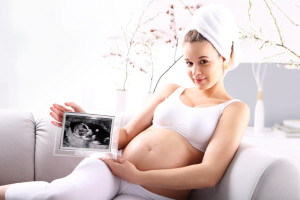 Kobieta w ciąży pokazuje usg dziecka